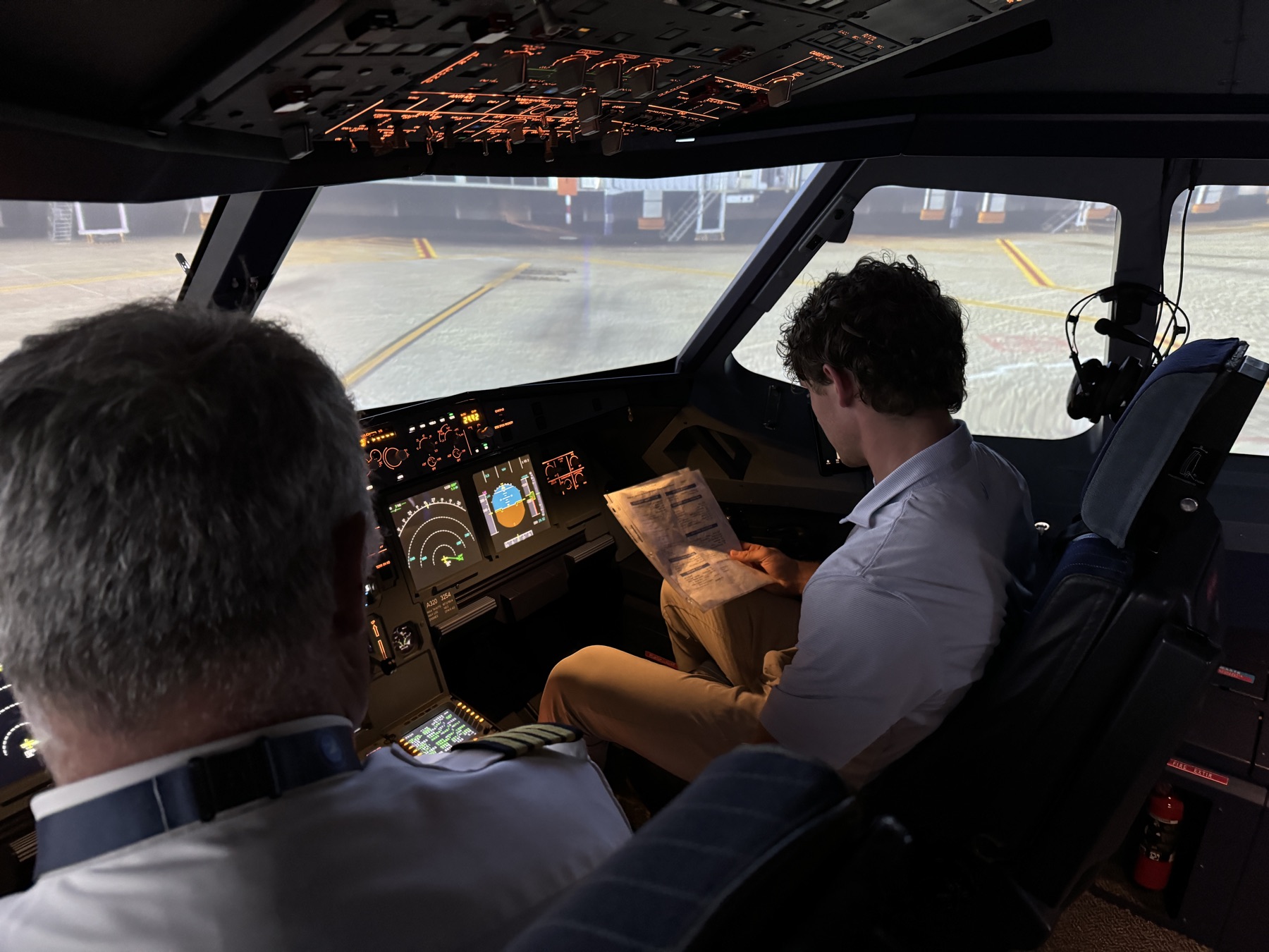 A student at the controls of a full-motion airline simulator beside a Delta captain